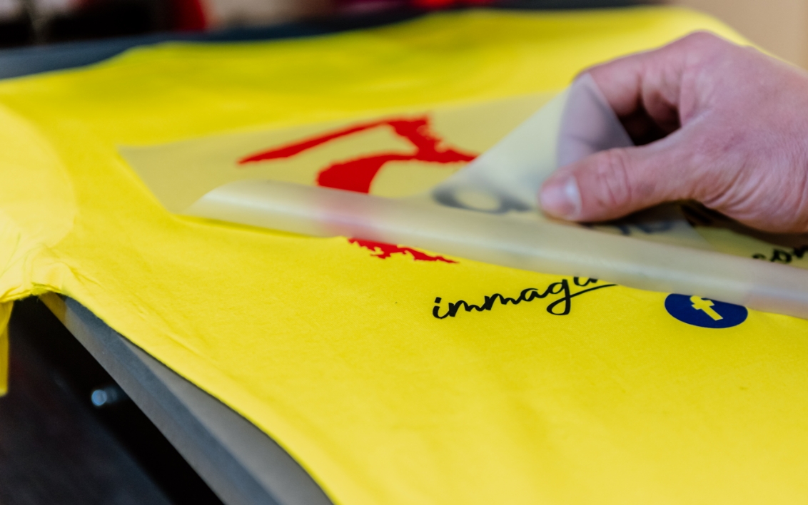 una mano spellicola un lavoro di grafica applicato su un tessuto